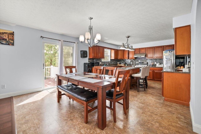 dining space with a notable chandelier, sink, and a textured ceiling