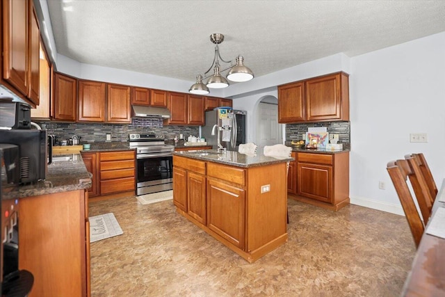 kitchen with decorative backsplash, dark stone counters, stainless steel appliances, decorative light fixtures, and an island with sink