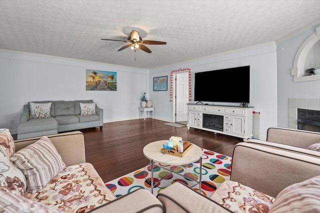 living room featuring a textured ceiling, ornamental molding, a fireplace, and dark wood-type flooring