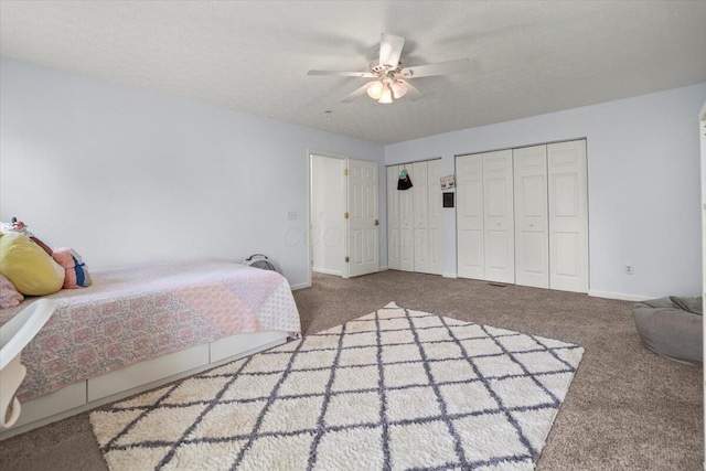 carpeted bedroom featuring multiple closets, ceiling fan, and a textured ceiling