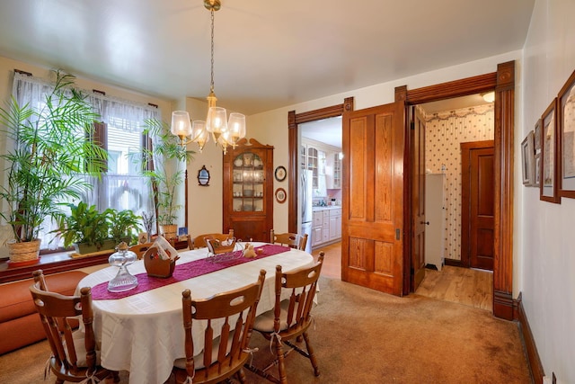 dining area with an inviting chandelier and light carpet