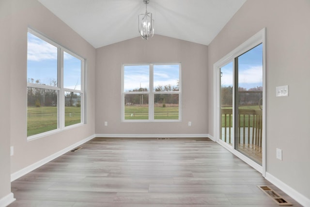 unfurnished dining area featuring a chandelier, a wealth of natural light, light hardwood / wood-style floors, and vaulted ceiling