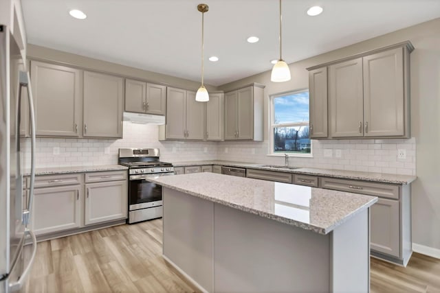 kitchen featuring sink, stainless steel appliances, light stone counters, light hardwood / wood-style flooring, and pendant lighting