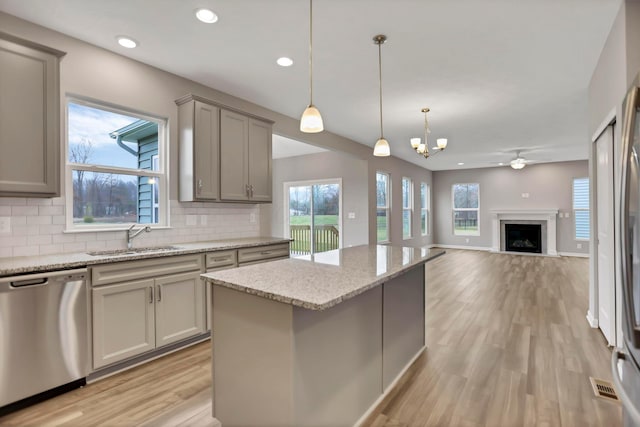 kitchen with stainless steel dishwasher, decorative light fixtures, backsplash, and sink