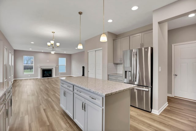 kitchen with backsplash, a center island, hanging light fixtures, and stainless steel refrigerator with ice dispenser