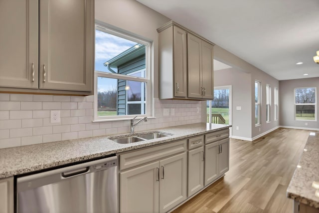 kitchen featuring light stone countertops, sink, tasteful backsplash, light hardwood / wood-style flooring, and stainless steel dishwasher