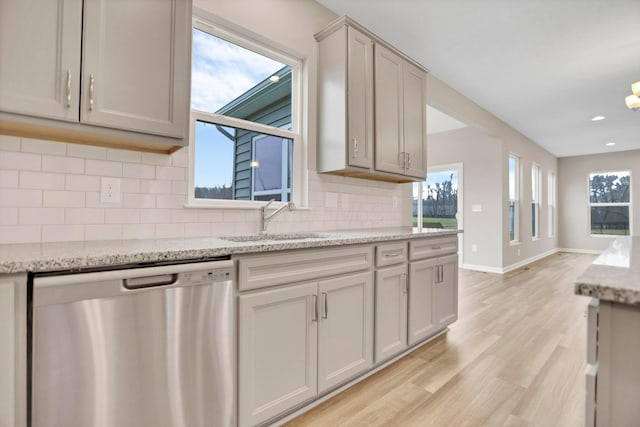 kitchen featuring light stone counters, stainless steel dishwasher, gray cabinetry, sink, and light hardwood / wood-style flooring