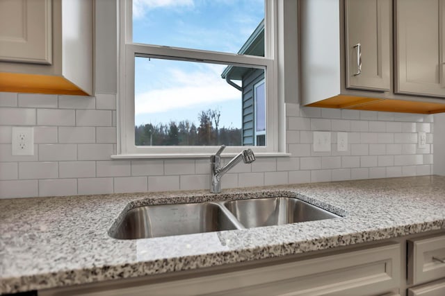 kitchen with sink, light stone countertops, and backsplash