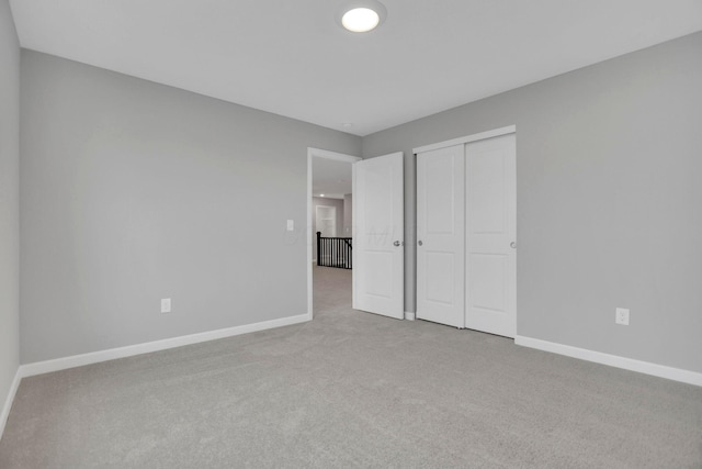 unfurnished bedroom featuring light carpet and a closet