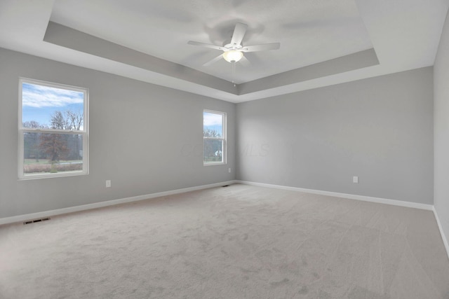 carpeted spare room with ceiling fan and a tray ceiling