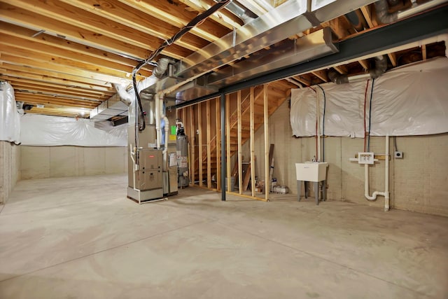 basement featuring heating unit, sink, and water heater