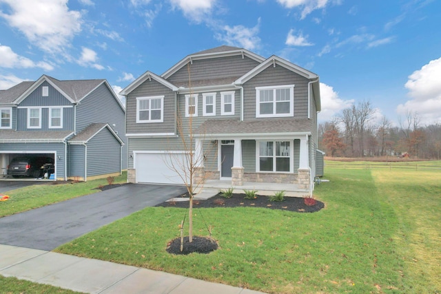 craftsman-style house featuring a front yard, a garage, and covered porch