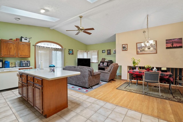 kitchen with ceiling fan with notable chandelier, dishwasher, a kitchen island, hanging light fixtures, and light tile patterned flooring