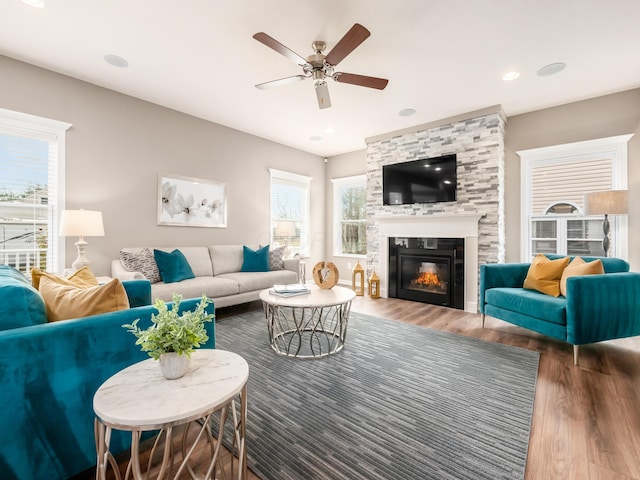 living room featuring hardwood / wood-style flooring, ceiling fan, and a fireplace