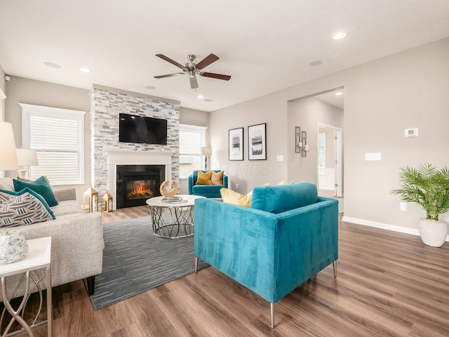 living room featuring a stone fireplace, ceiling fan, and hardwood / wood-style flooring