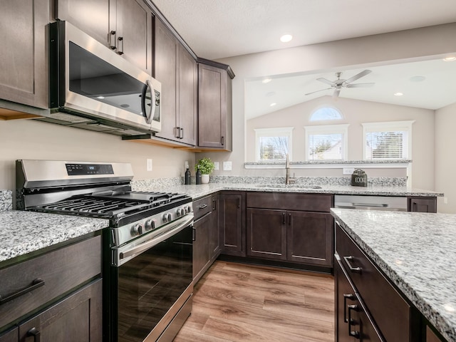 kitchen featuring appliances with stainless steel finishes, ceiling fan, sink, light hardwood / wood-style flooring, and lofted ceiling