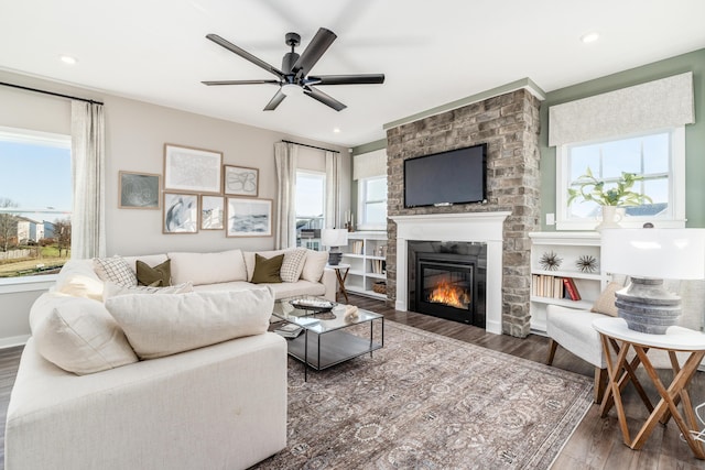 living room featuring a large fireplace, dark hardwood / wood-style floors, and ceiling fan