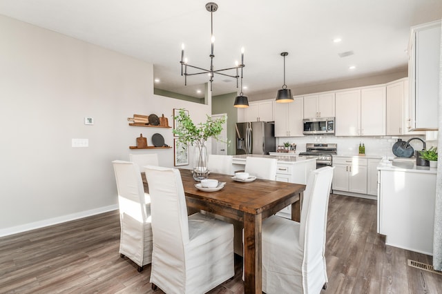 dining area with dark hardwood / wood-style floors, sink, and an inviting chandelier