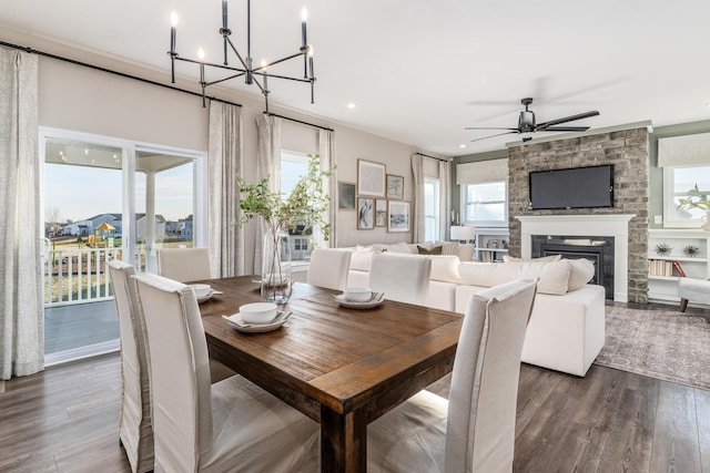 dining room featuring a fireplace, ceiling fan with notable chandelier, and dark hardwood / wood-style floors