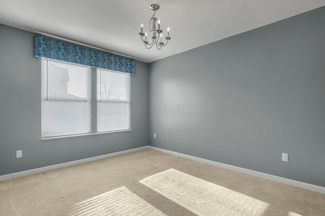 carpeted spare room featuring a chandelier