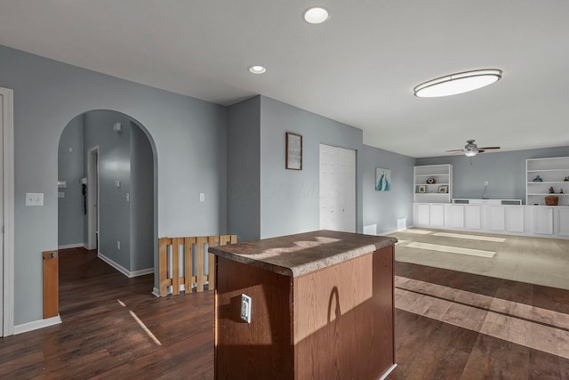 kitchen featuring built in shelves, a center island, dark hardwood / wood-style floors, and ceiling fan