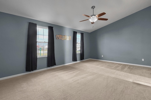 carpeted empty room with ceiling fan, a healthy amount of sunlight, and vaulted ceiling