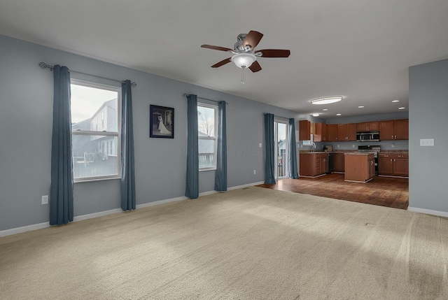 unfurnished living room with dark colored carpet, ceiling fan, and sink