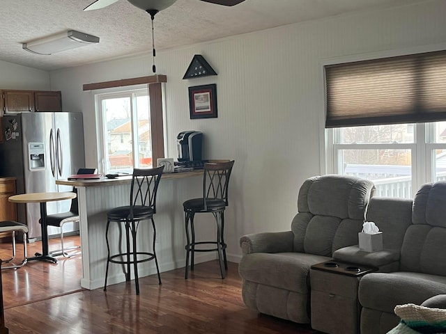 living room featuring ceiling fan, a textured ceiling, and dark wood-type flooring