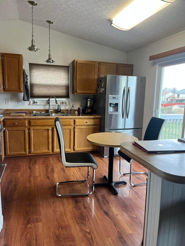 kitchen featuring stainless steel fridge, dark hardwood / wood-style flooring, sink, hanging light fixtures, and lofted ceiling