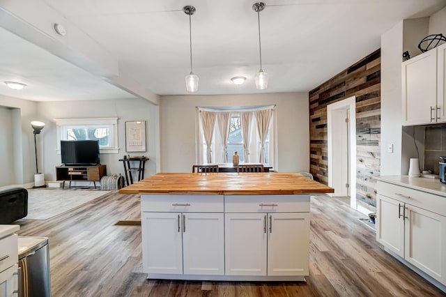 kitchen featuring a healthy amount of sunlight, butcher block counters, white cabinetry, and hanging light fixtures