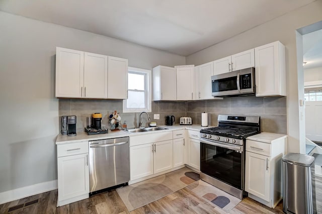 kitchen with tasteful backsplash, sink, white cabinets, and stainless steel appliances