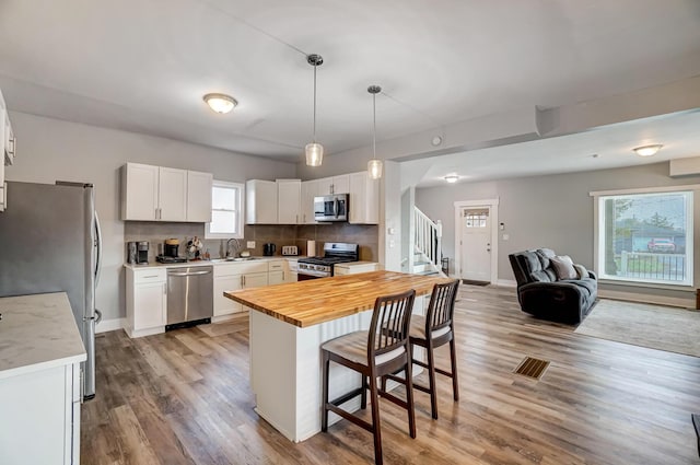 kitchen featuring wooden counters, appliances with stainless steel finishes, decorative backsplash, sink, and white cabinets