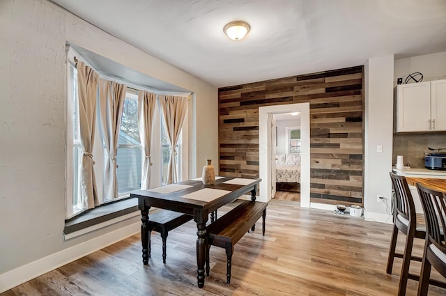 dining space with wood walls and light hardwood / wood-style floors