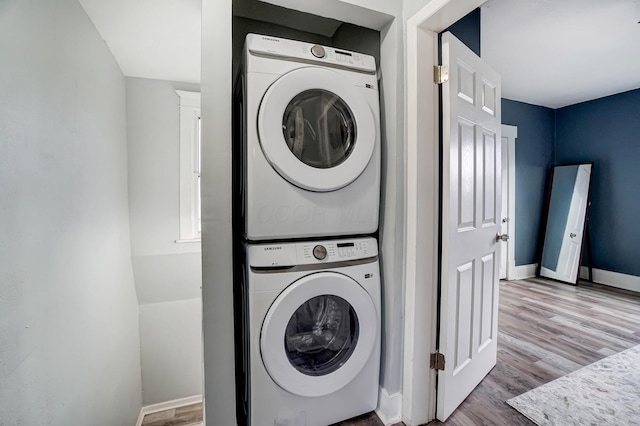 laundry room featuring light wood-type flooring and stacked washer / dryer