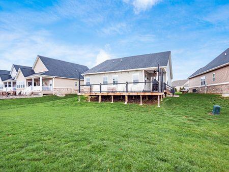 rear view of house featuring a lawn and a deck