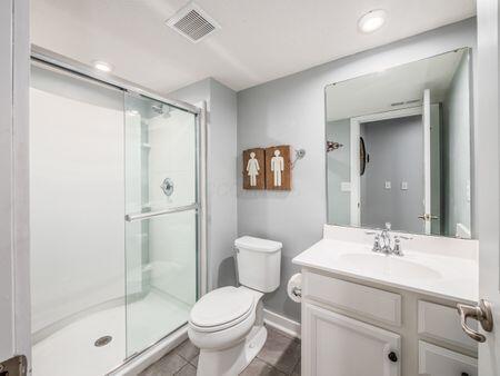 bathroom featuring tile patterned floors, vanity, an enclosed shower, and toilet