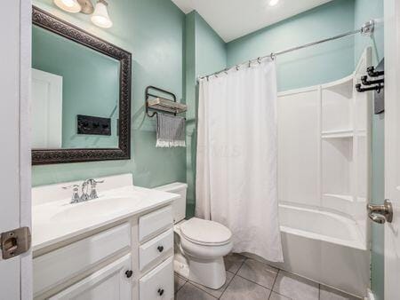 full bathroom with tile patterned flooring, shower / bath combo, vanity, and toilet