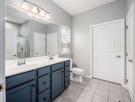 bathroom featuring tile patterned floors, vanity, a shower with shower door, and toilet