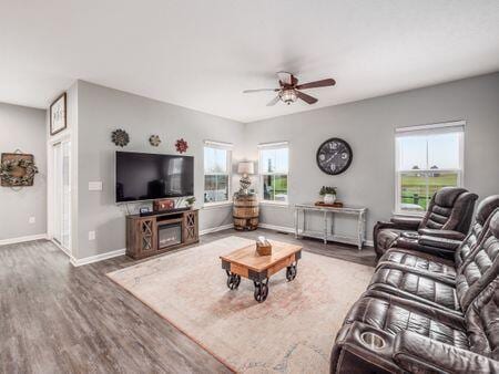 living room with a wealth of natural light, ceiling fan, and dark hardwood / wood-style flooring