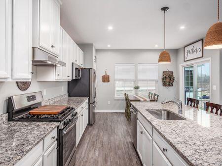 kitchen featuring light stone countertops, stainless steel appliances, sink, pendant lighting, and white cabinetry