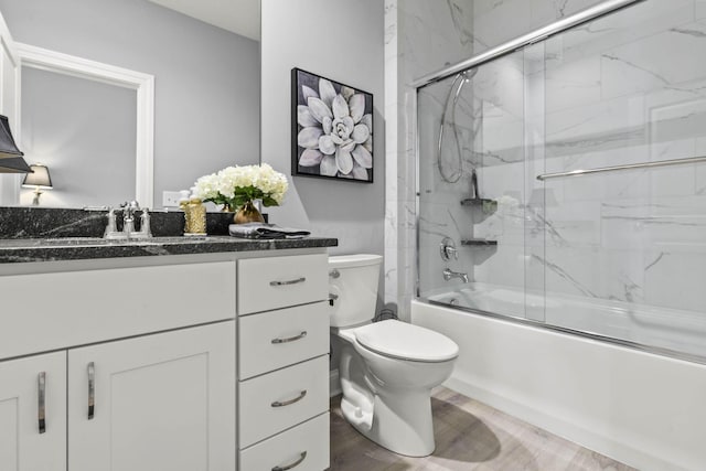 full bathroom featuring toilet, vanity, wood-type flooring, and combined bath / shower with glass door