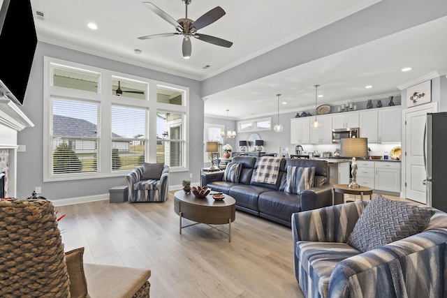 living room with ceiling fan with notable chandelier, light hardwood / wood-style floors, and crown molding