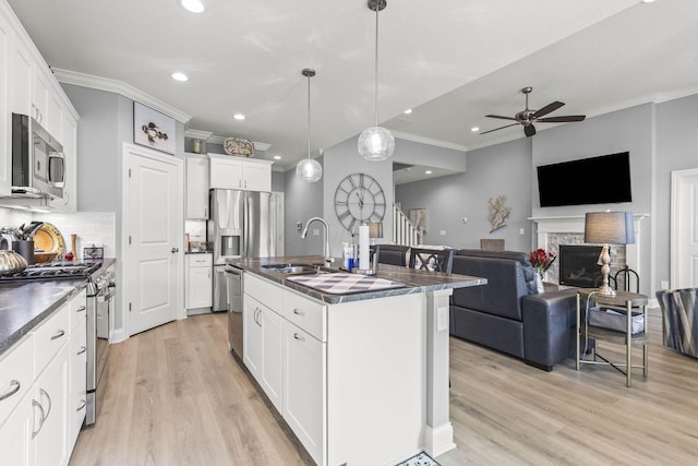 kitchen with white cabinets, appliances with stainless steel finishes, sink, and an island with sink