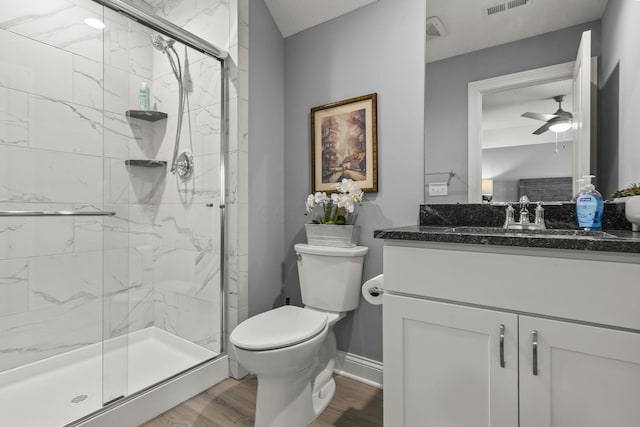 bathroom with vanity, hardwood / wood-style flooring, ceiling fan, toilet, and a shower with shower door