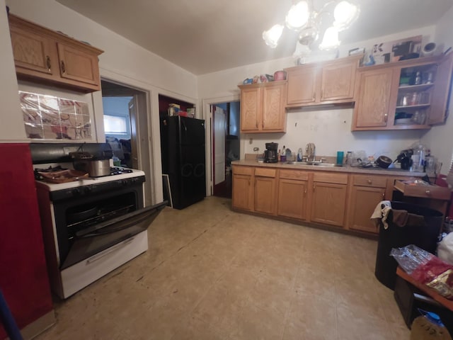 kitchen with a chandelier, black refrigerator, sink, and gas range gas stove