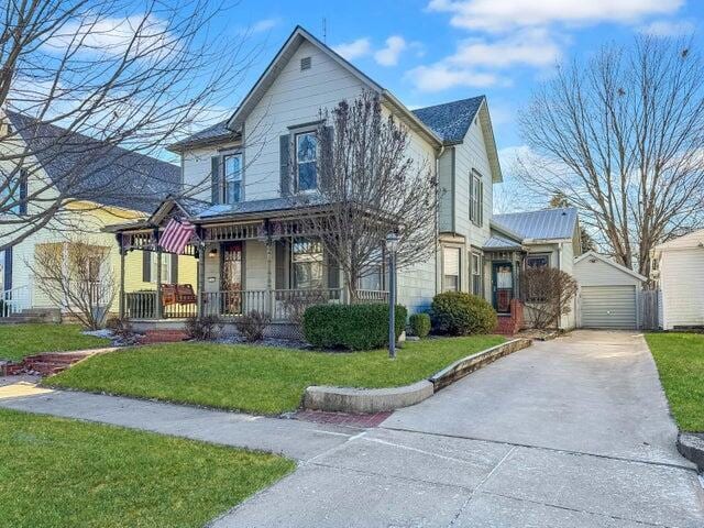 view of front of house with a garage, covered porch, an outdoor structure, and a front yard