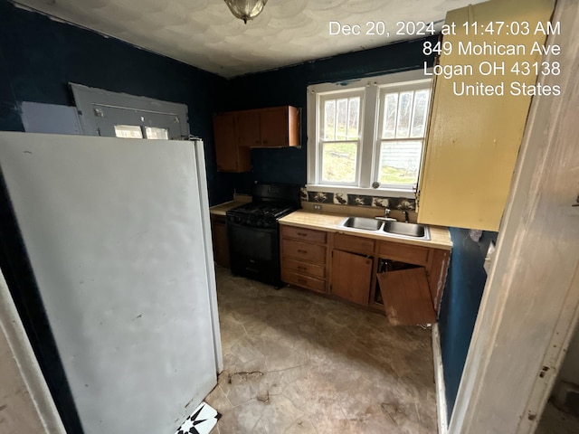 kitchen featuring black gas range, sink, and fridge