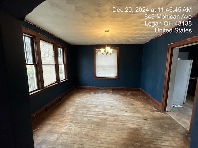 unfurnished dining area with a notable chandelier and wood-type flooring