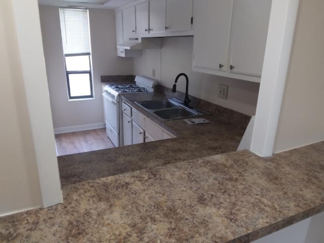 kitchen with white range with gas stovetop, white cabinetry, extractor fan, and sink