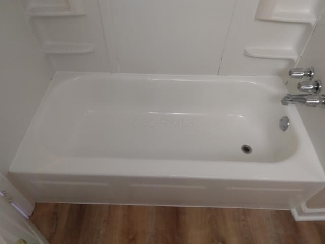 bathroom with shower / washtub combination and hardwood / wood-style floors